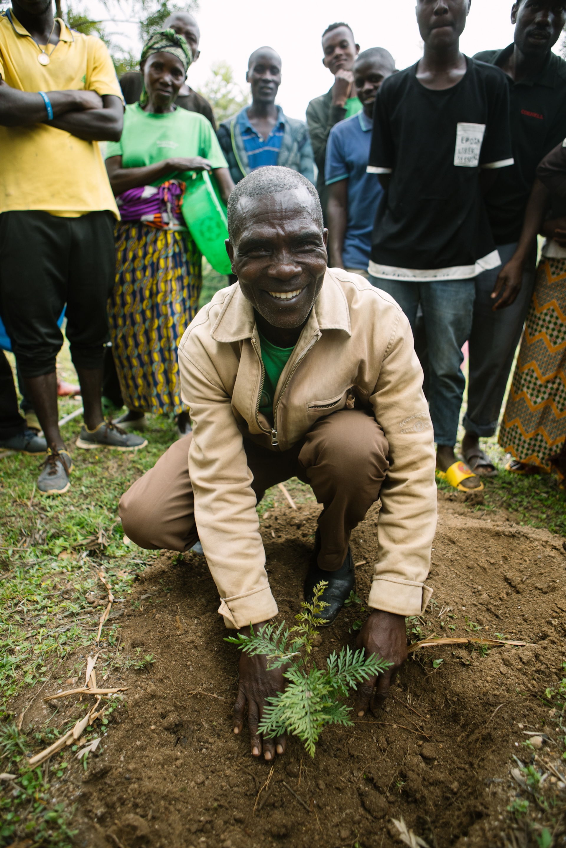 A man smiling as he plants a tree